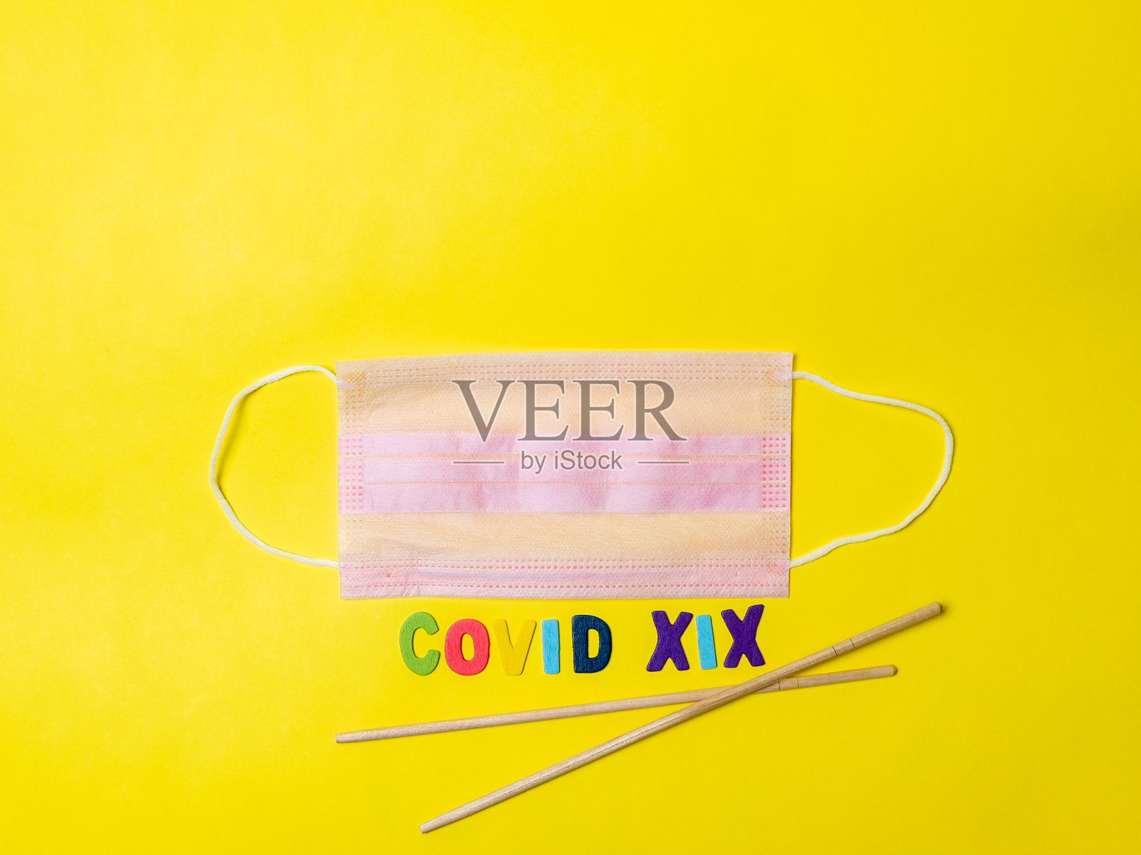 黄色背景的黑色医用口罩和字母v形状的亚洲筷子。照片摄影图片