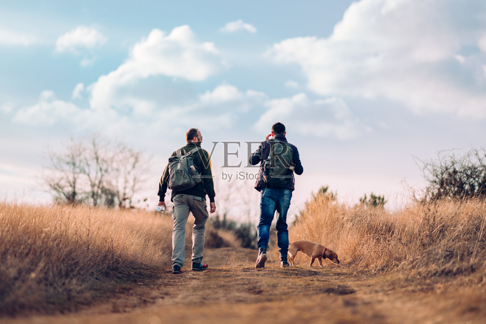 两个朋友带着狗一起徒步旅行照片摄影图片
