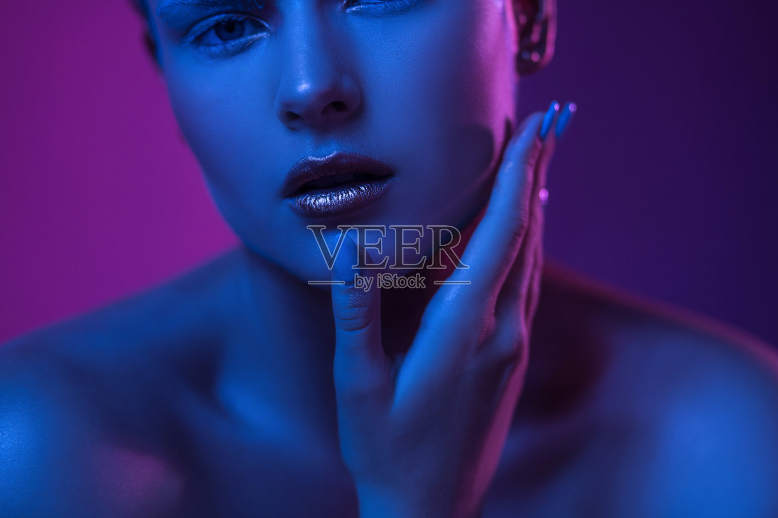年轻性感的女人与开放的嘴唇在紫色的蓝色霓虹灯照片摄影图片