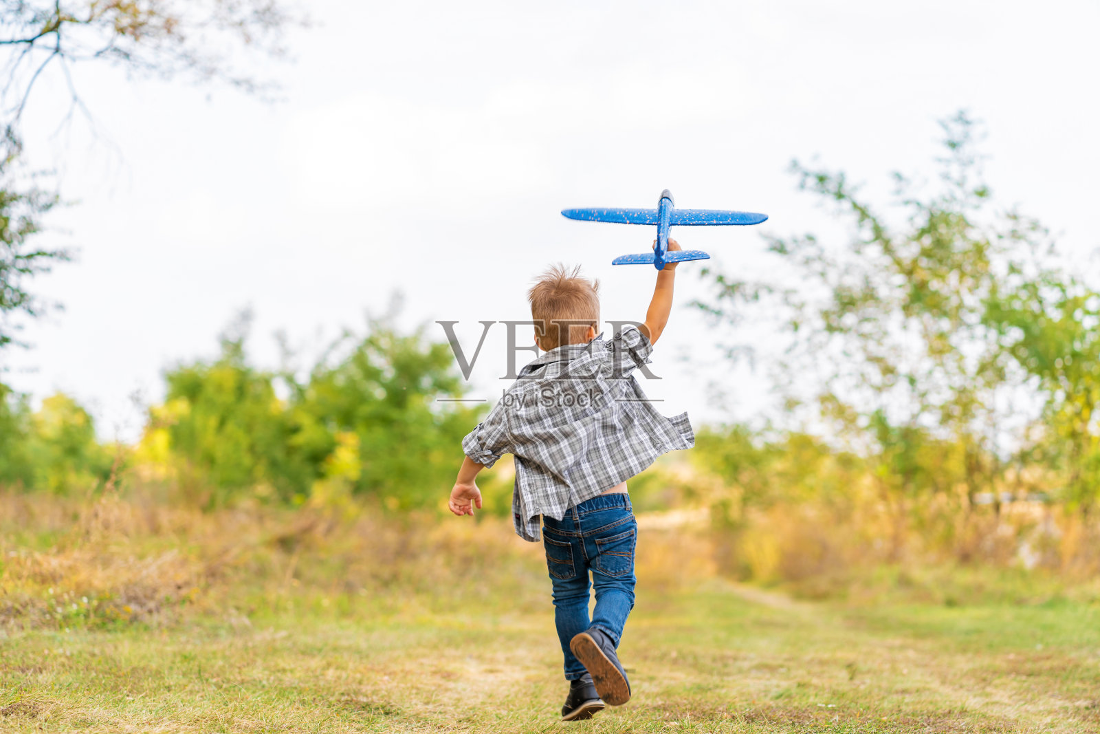 快乐的男孩在公园户外玩玩具飞机照片摄影图片