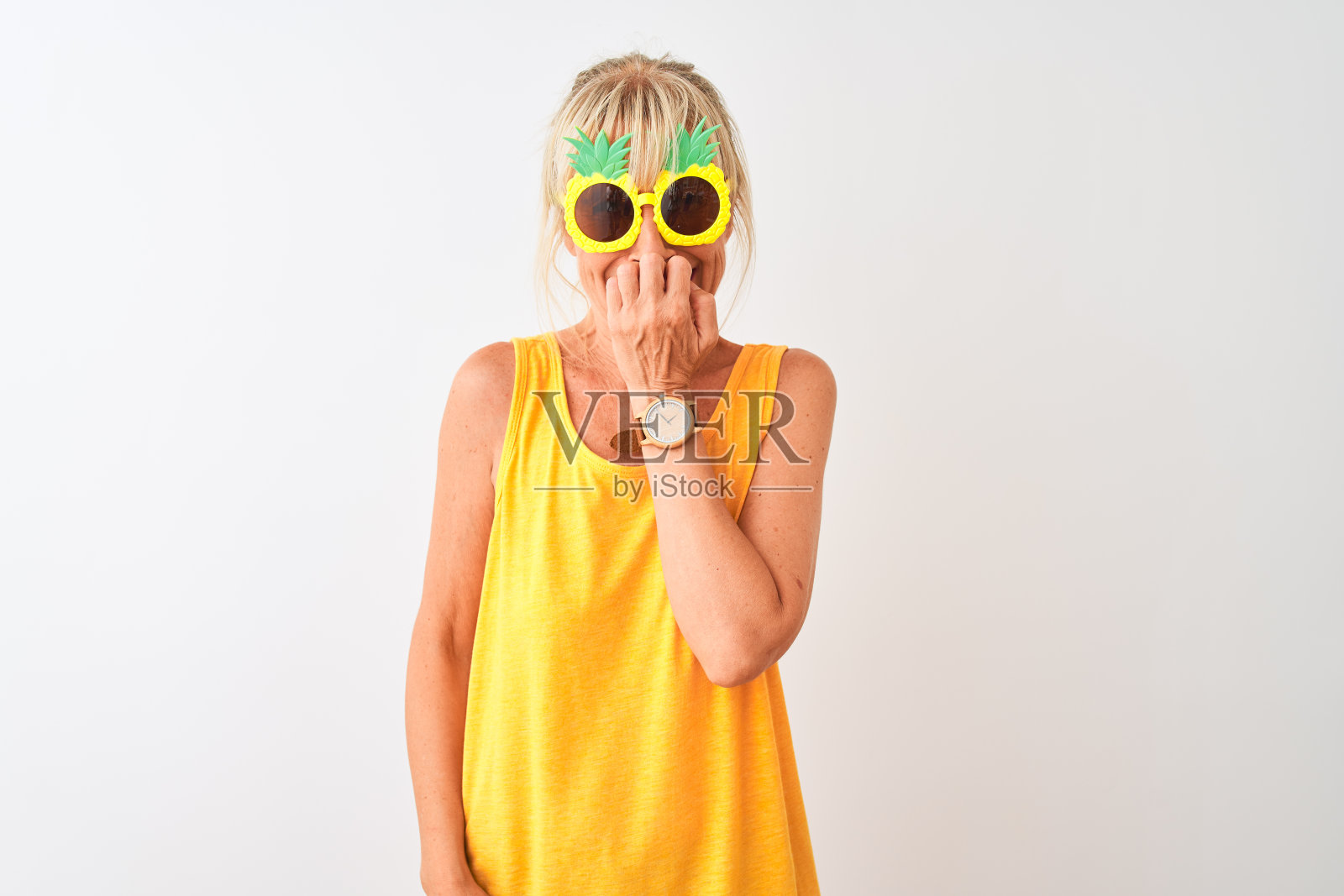 在白色背景上戴着菠萝太阳镜度假的中年妇女,手捂着嘴,咬着指甲,显得紧张不安,有焦虑问题照片摄影图片
