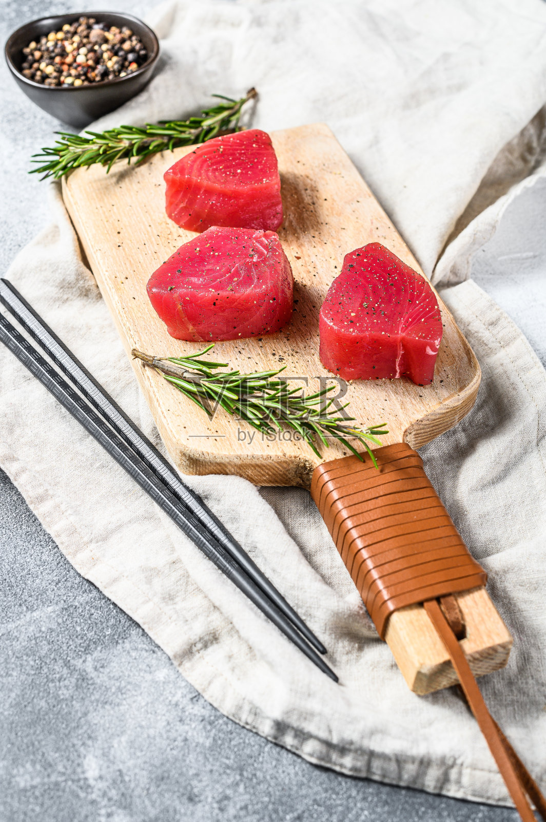 切菜板上的新鲜金枪鱼排。灰色的背景。俯视图照片摄影图片