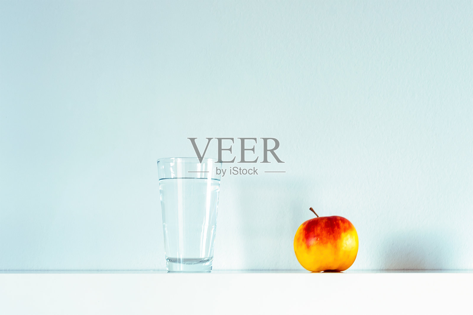 架子上放着一杯水和苹果,健康生活理念,白色背景照片摄影图片