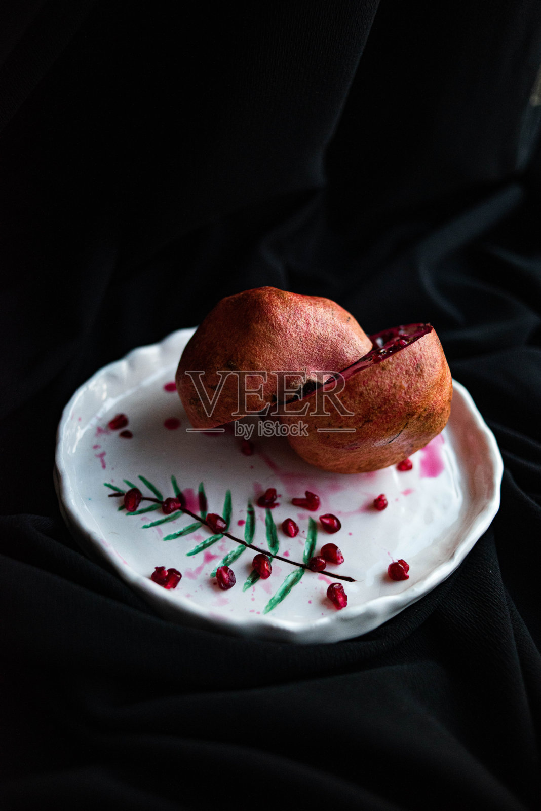 将石榴切成中间,放在瓷盘上照片摄影图片