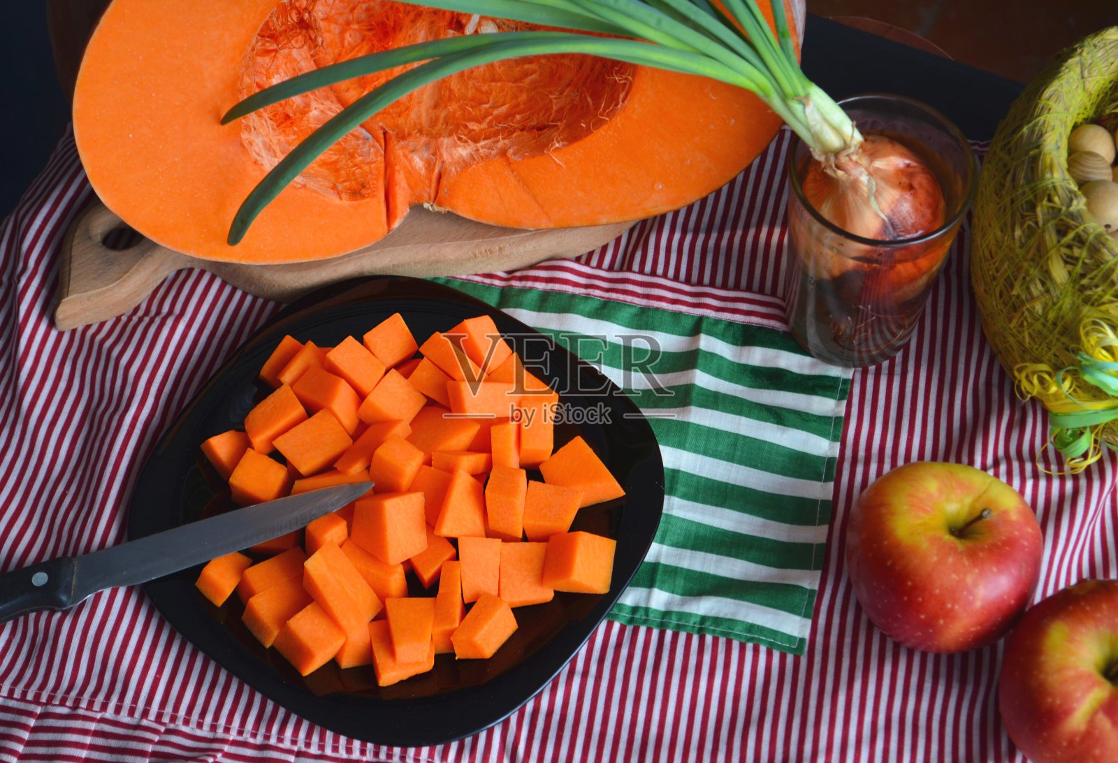 新鲜的生南瓜,切成小方块。Gray-orange背景。素食菜。照片摄影图片