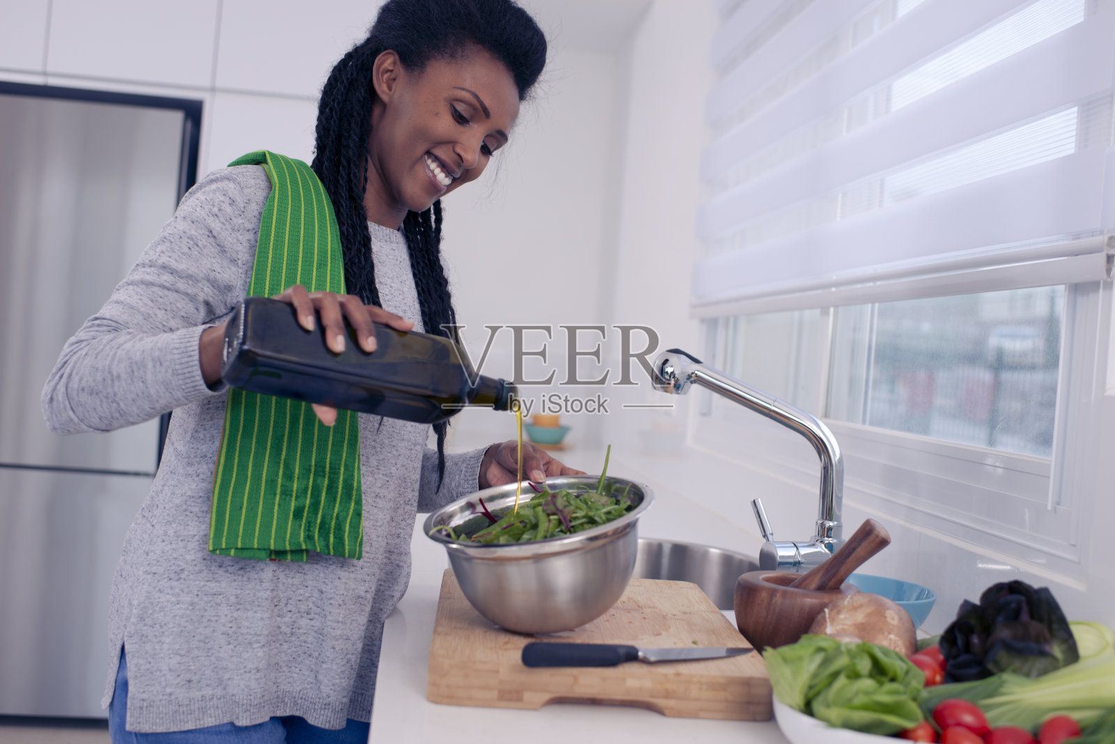 女人准备沙拉,用橄榄油调味照片摄影图片