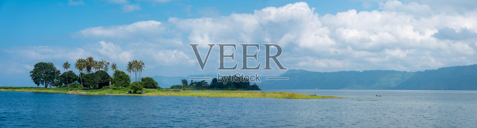 一个美丽的绿色岛屿在美丽的蓝色热带水域的多巴湖在印度尼西亚照片摄影图片