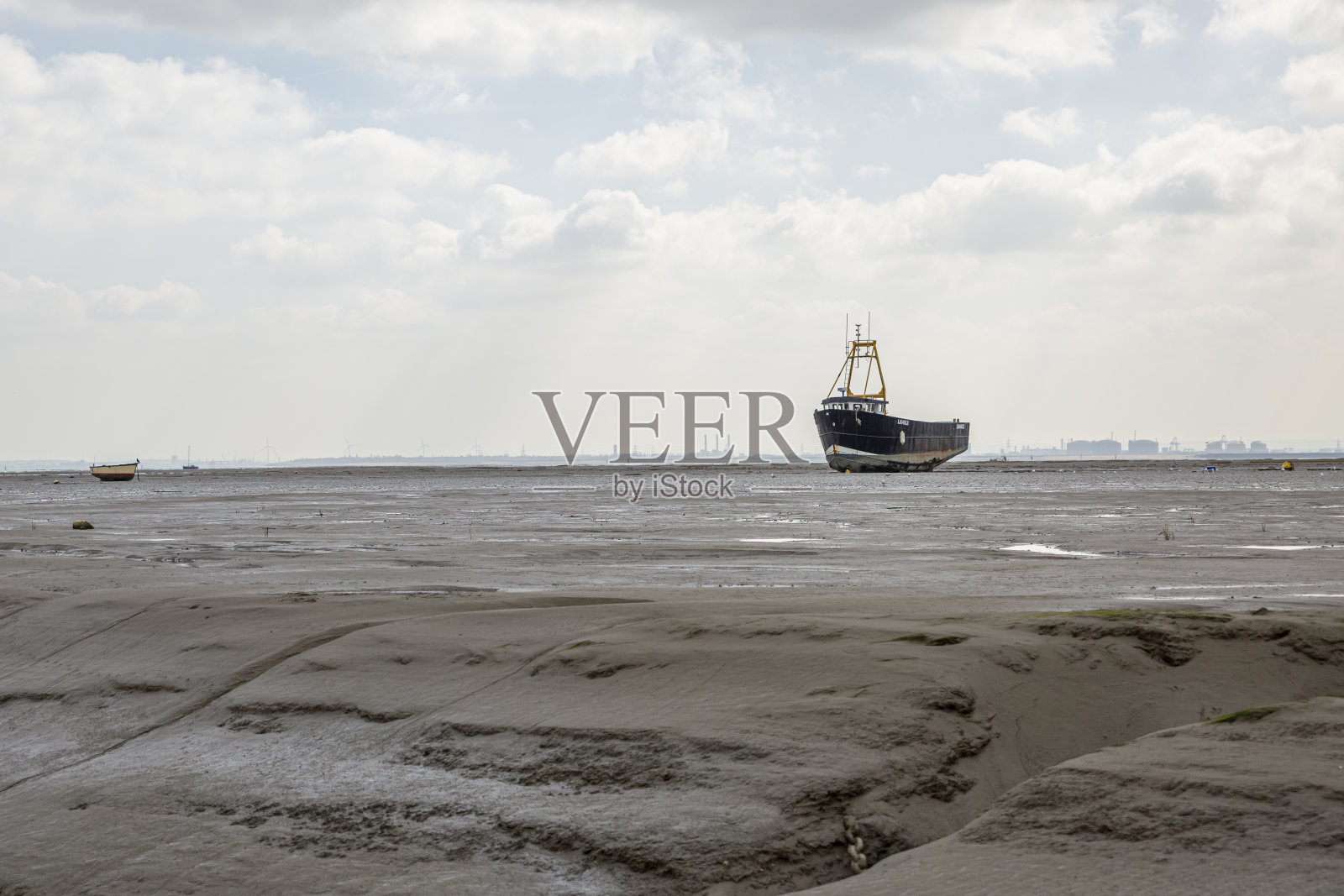 退潮时,渔船搁浅在海滩上。照片摄影图片