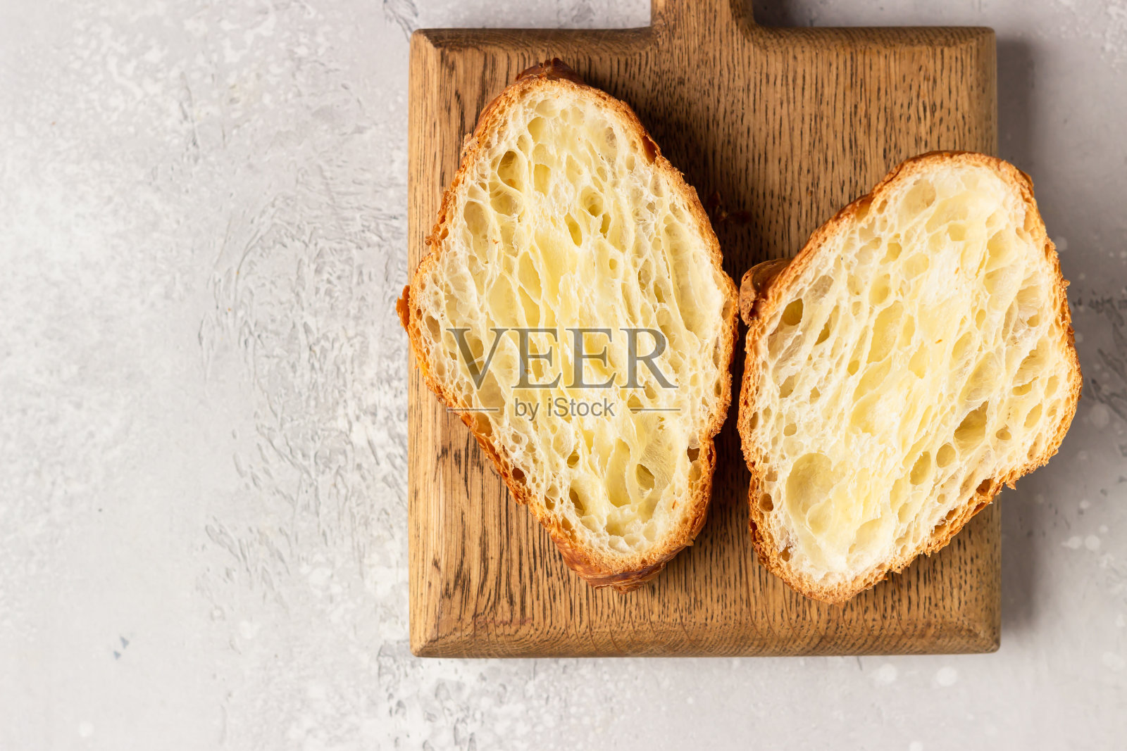 把牛角面包切成两半,放在木砧板上做三明治。自制新鲜金色牛角面包。照片摄影图片