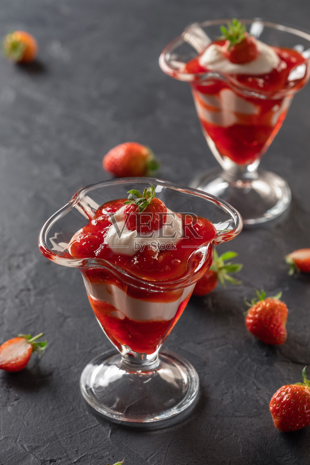 奶油甜点与新鲜的草莓和草莓酱在一个玻璃碗在黑暗的背景照片摄影图片