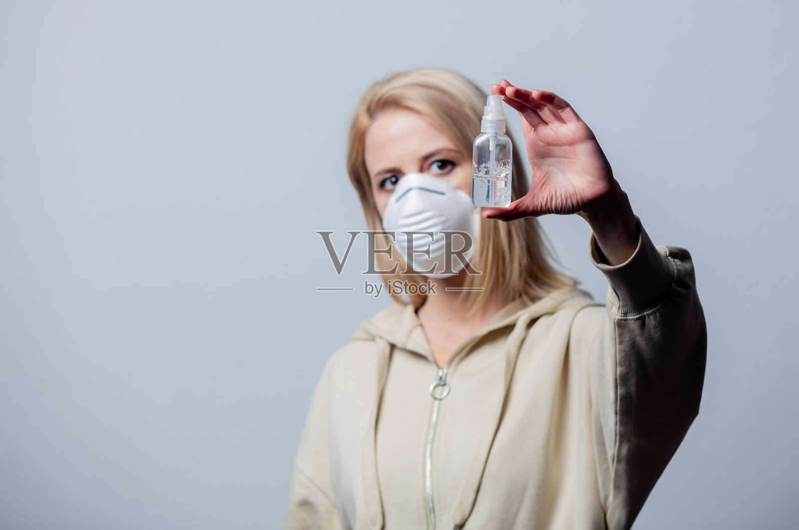 金发女子戴防护口罩手持消毒凝胶照片摄影图片