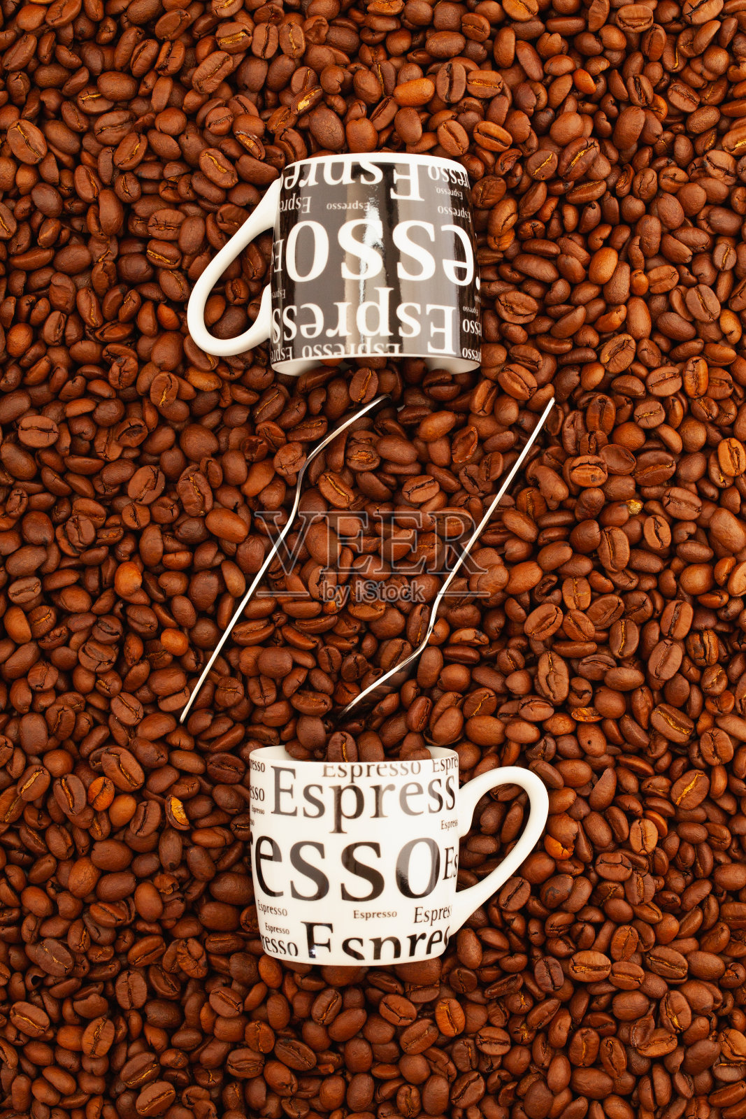 两杯咖啡放在装满咖啡豆的桌子上。照片摄影图片