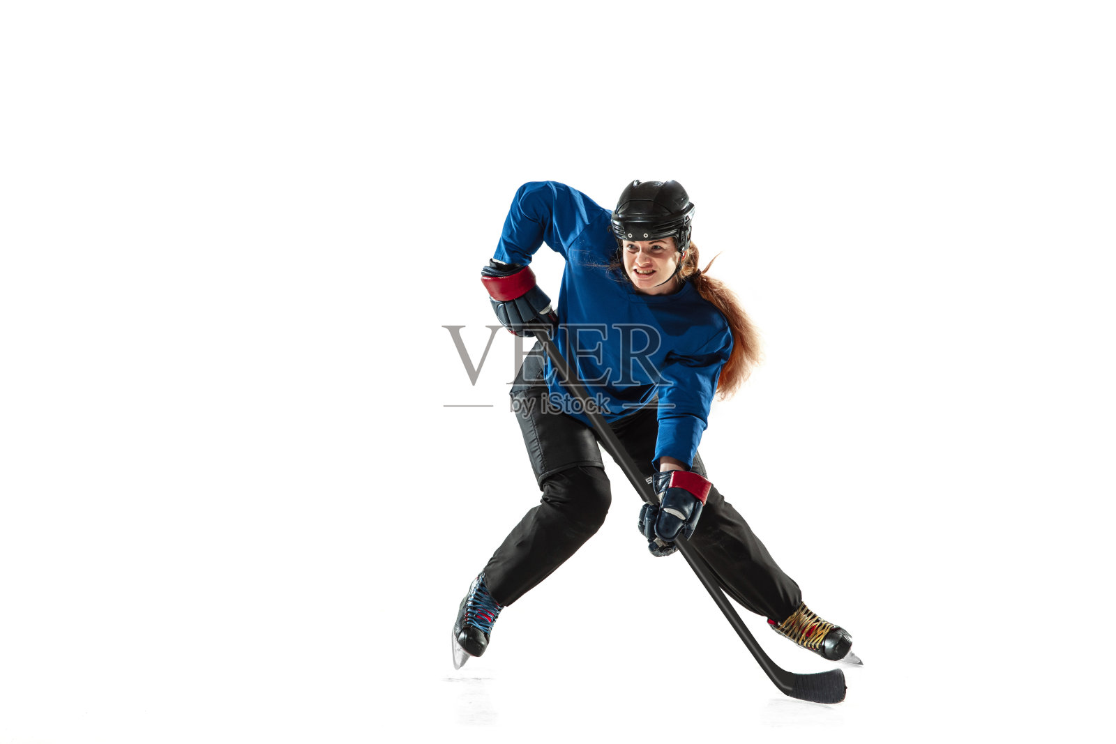 年轻女曲棍球运动员手持球杆站在冰场上,白色背景照片摄影图片