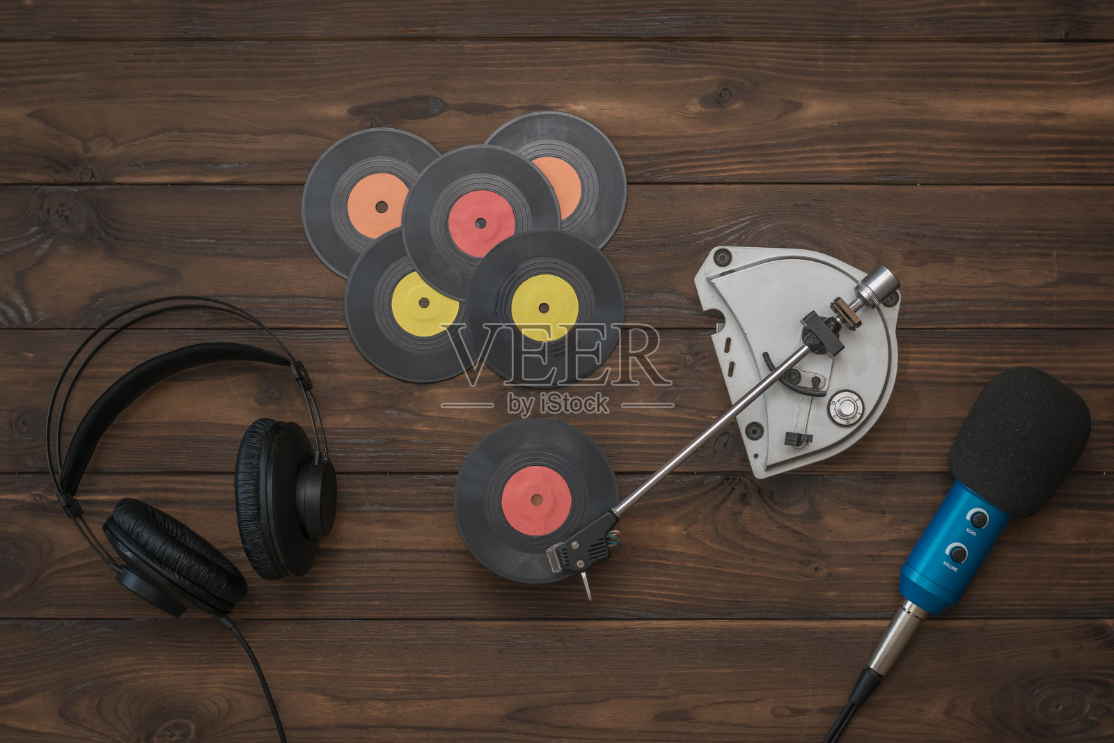 木桌上放着耳机、麦克风和老式唱片机。照片摄影图片