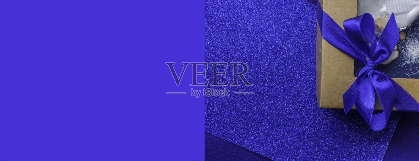 组成节日礼品包装的礼品盒与蓝色缎子蝴蝶结在时尚的蓝色背景,复制空间照片摄影图片