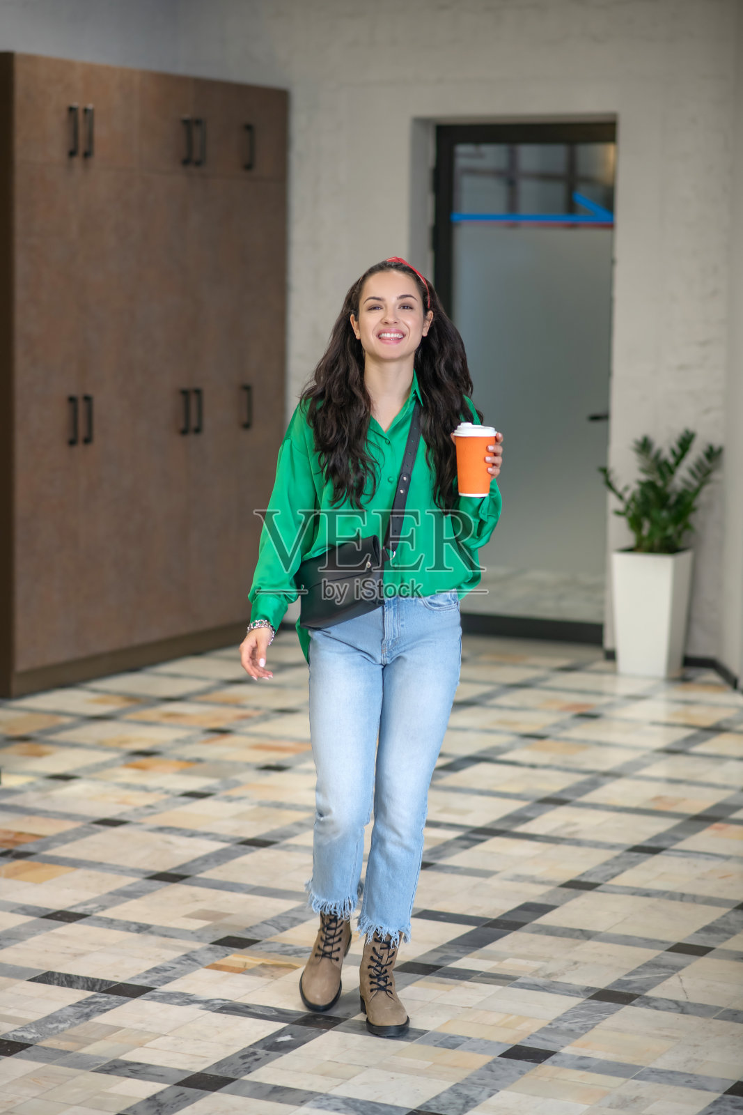 优雅的女人拿着咖啡沿着走廊走。照片摄影图片