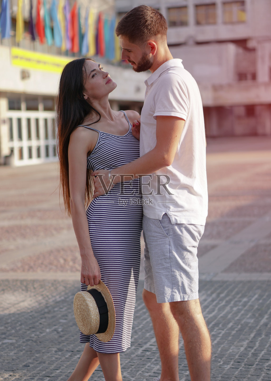 一对美丽的男人和女人在混凝土城市房屋的背景。一个女孩和一个男孩的浪漫主题。春天,夏天照片关系,爱情,情人节照片摄影图片