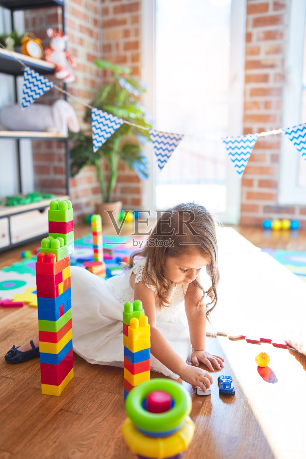 可爱的金发小孩玩积木周围的玩具在幼儿园照片摄影图片