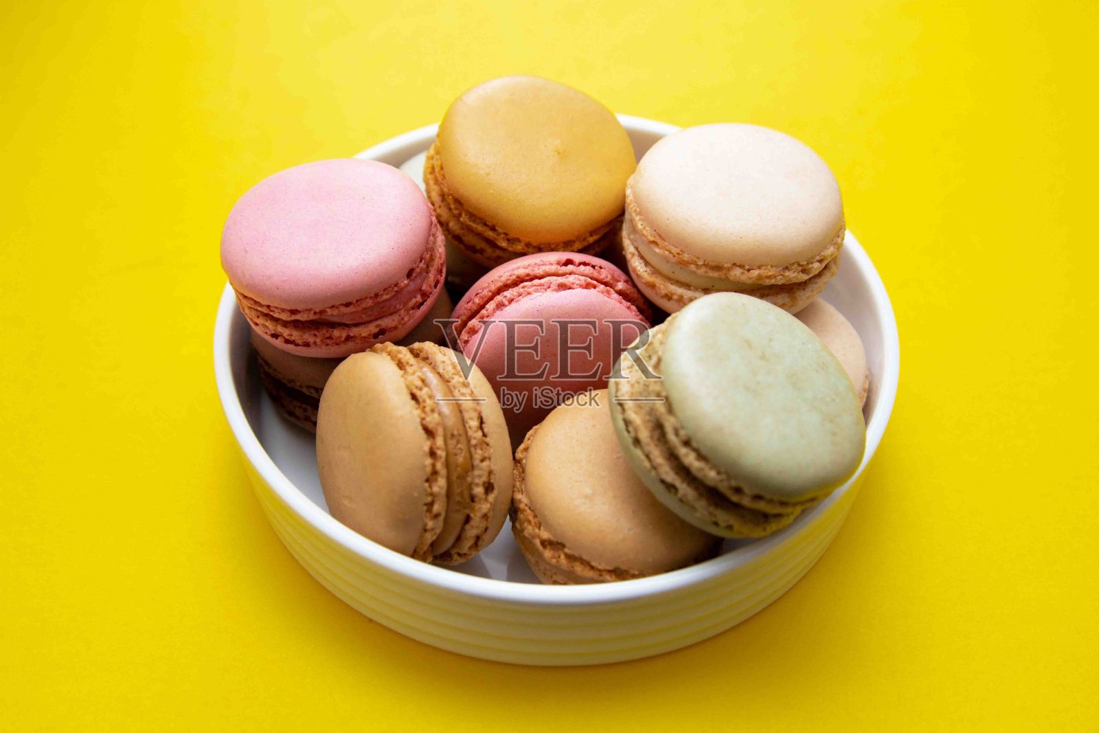 彩色的杏仁饼干甜点盘,以黄色为背景。照片摄影图片