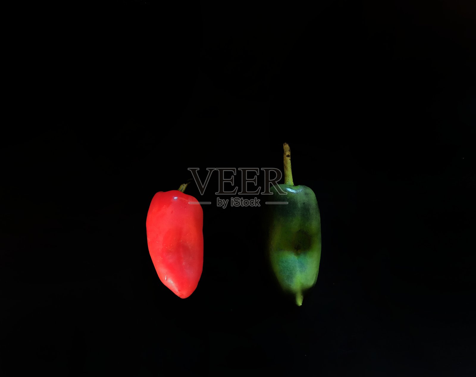 红辣椒在黑色背景上呈绿色和红色。健康食品的概念照片摄影图片