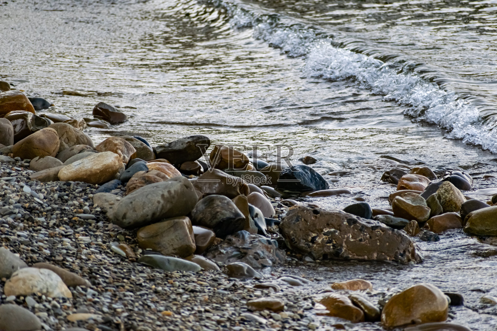 巨大而光滑的石头在咸海水的海岸波浪中。黑海海岸泛着泡沫,咆哮着照片摄影图片