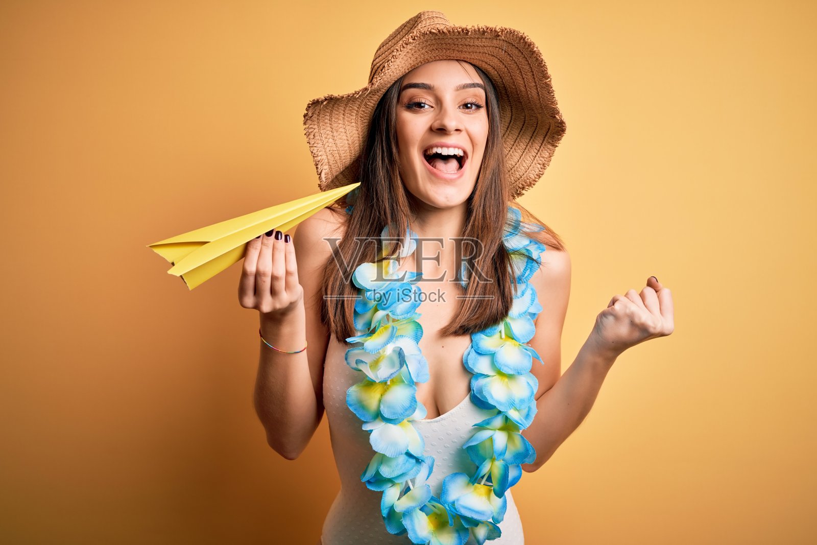 年轻美丽的女人在度假穿着比基尼和夏威夷蕾拿着纸飞机尖叫自豪和庆祝胜利和成功非常兴奋,欢呼的情绪照片摄影图片