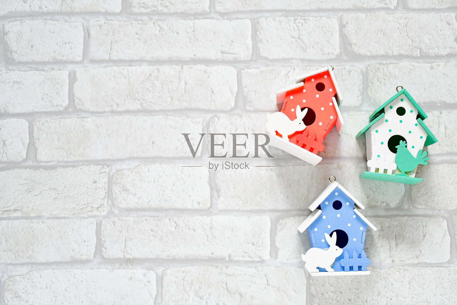 顶视图可爱的小装饰复活节房子在粉红色,红色,蓝色和绿色粉彩在白色砖墙的背景。复活节和春天的背景概念。照片摄影图片