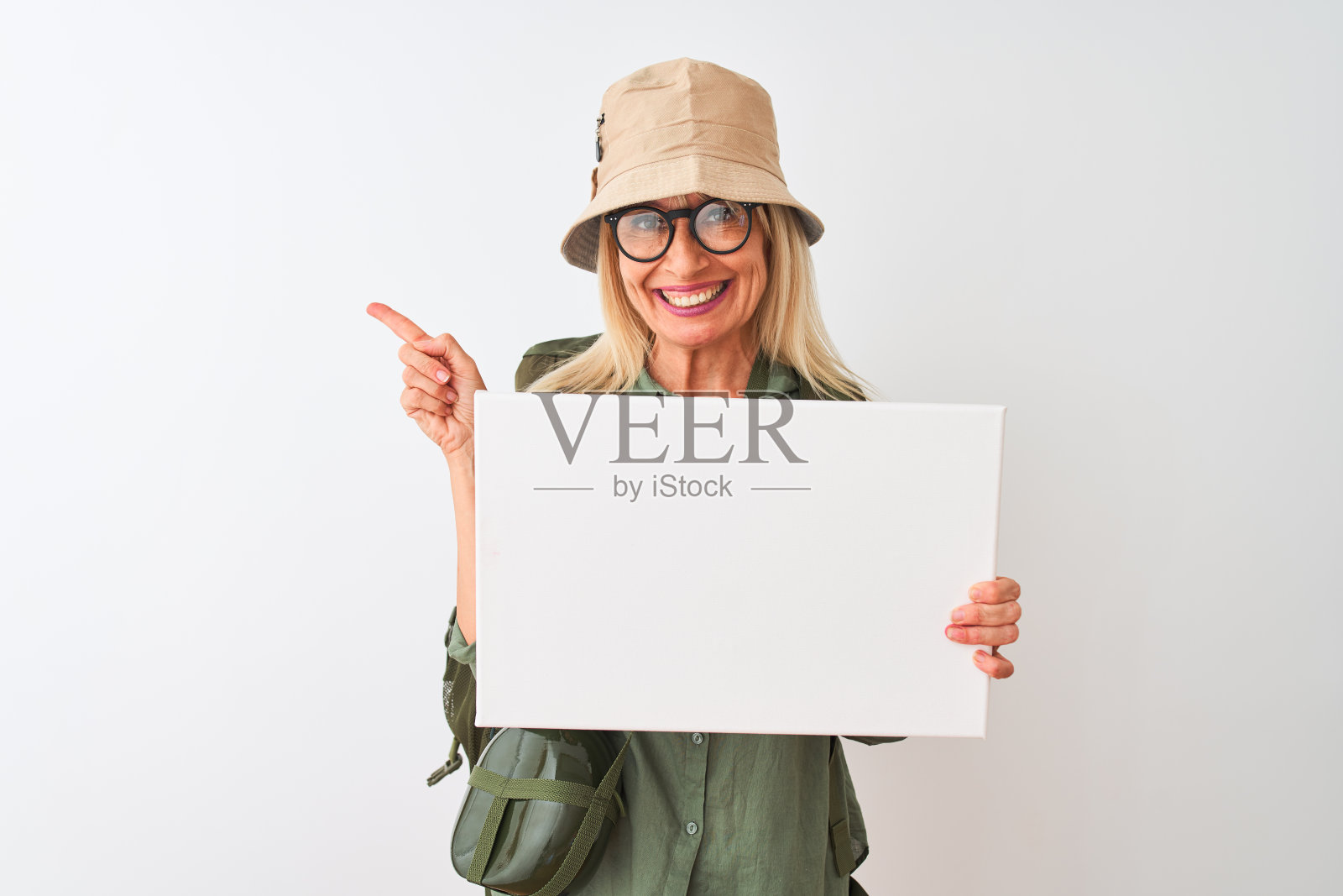 徒步妇女戴着食堂帽,举着旗帜在孤立的白色背景非常高兴地用手和手指指向一边照片摄影图片