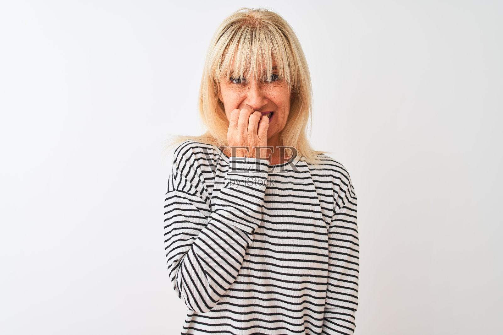中年妇女穿着海军蓝条纹T恤,看起来紧张焦虑,手放在嘴边咬指甲照片摄影图片
