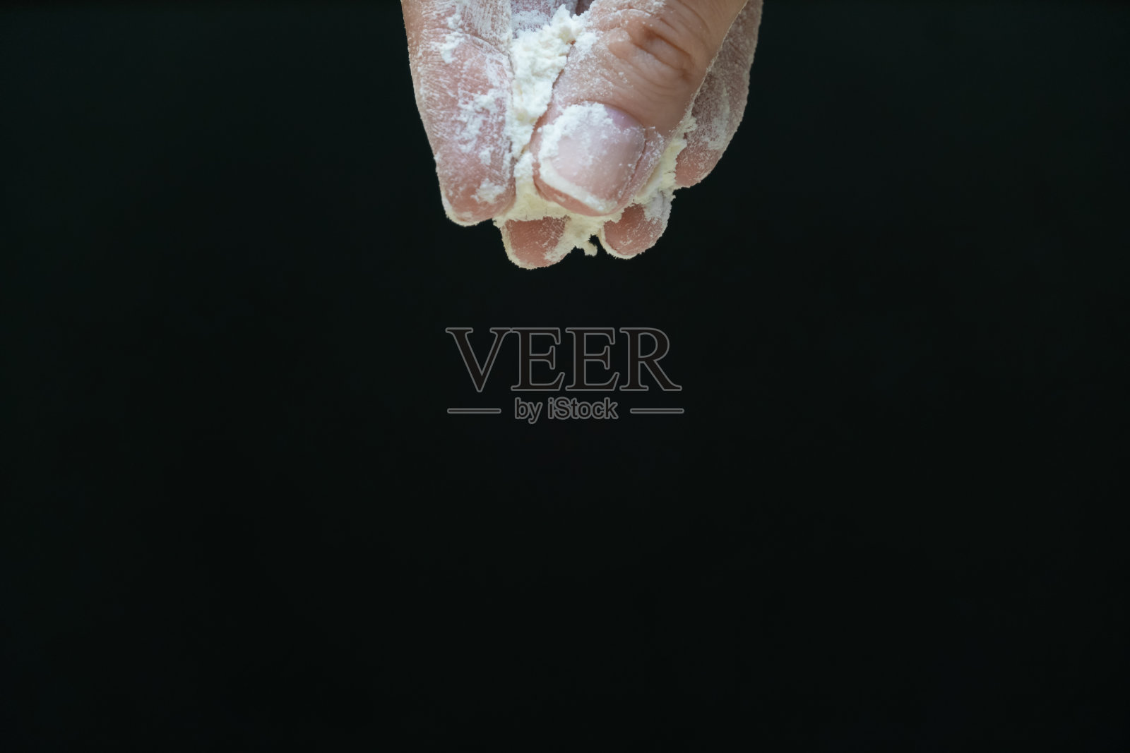 女性手指按住面粉在黑色背景与复制空间。在黑色背景上加少许面粉照片摄影图片