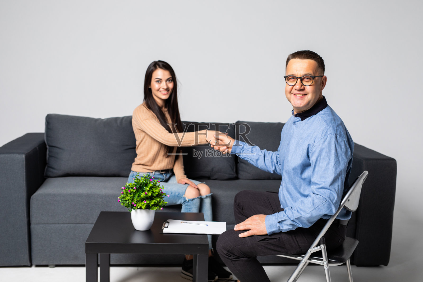 中年男治疗师欢迎新患者进入治疗室照片摄影图片