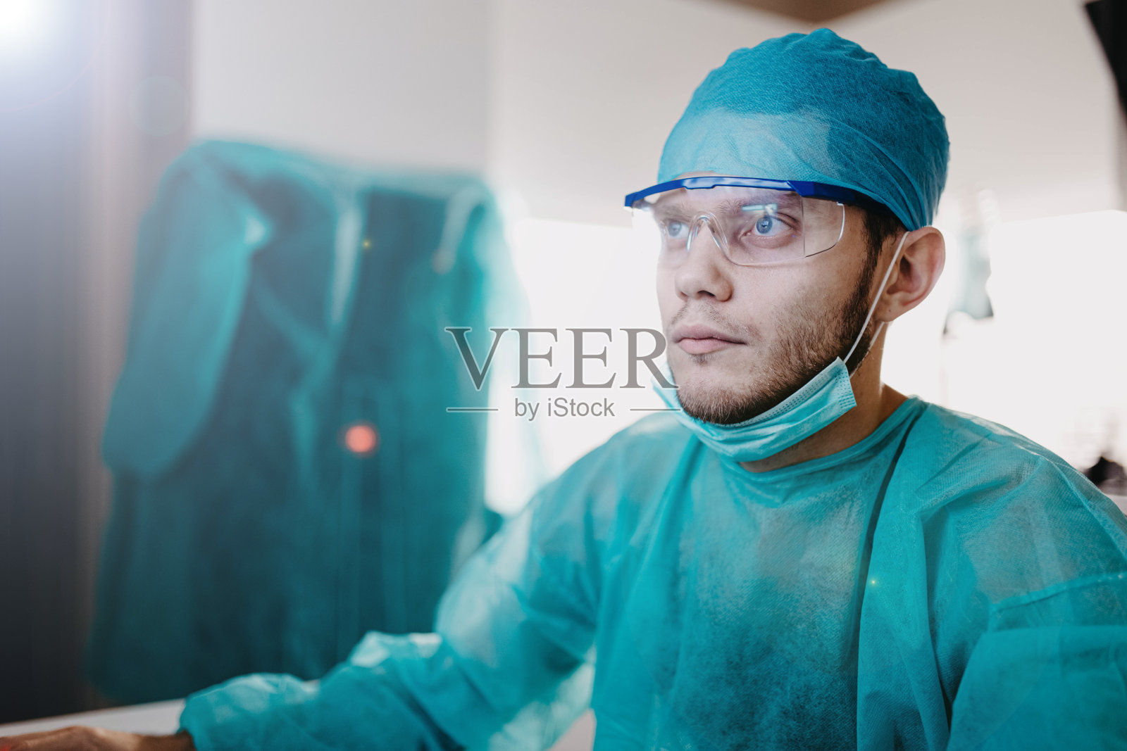 戴着制服口罩和眼镜的医生在医疗办公室工作,疫情概念照片摄影图片