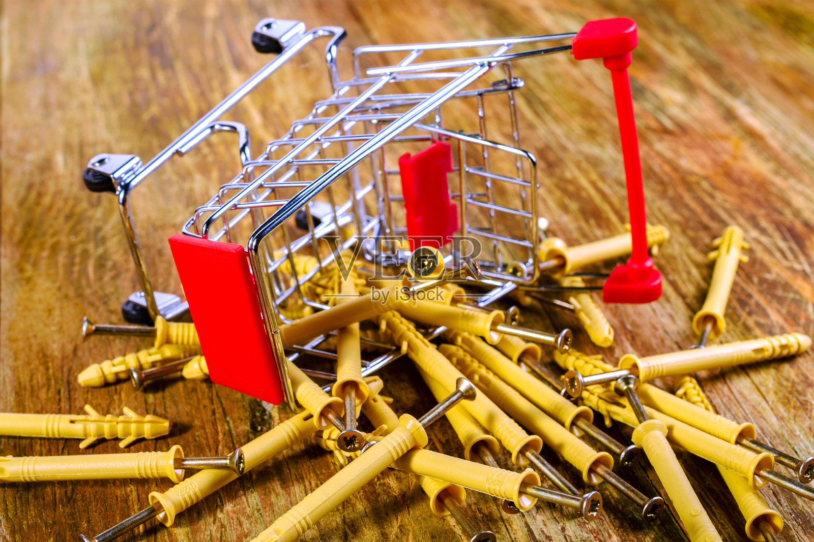 微型购物车里堆着一堆塑料销子和金属螺丝。购物家居维修概念。照片摄影图片