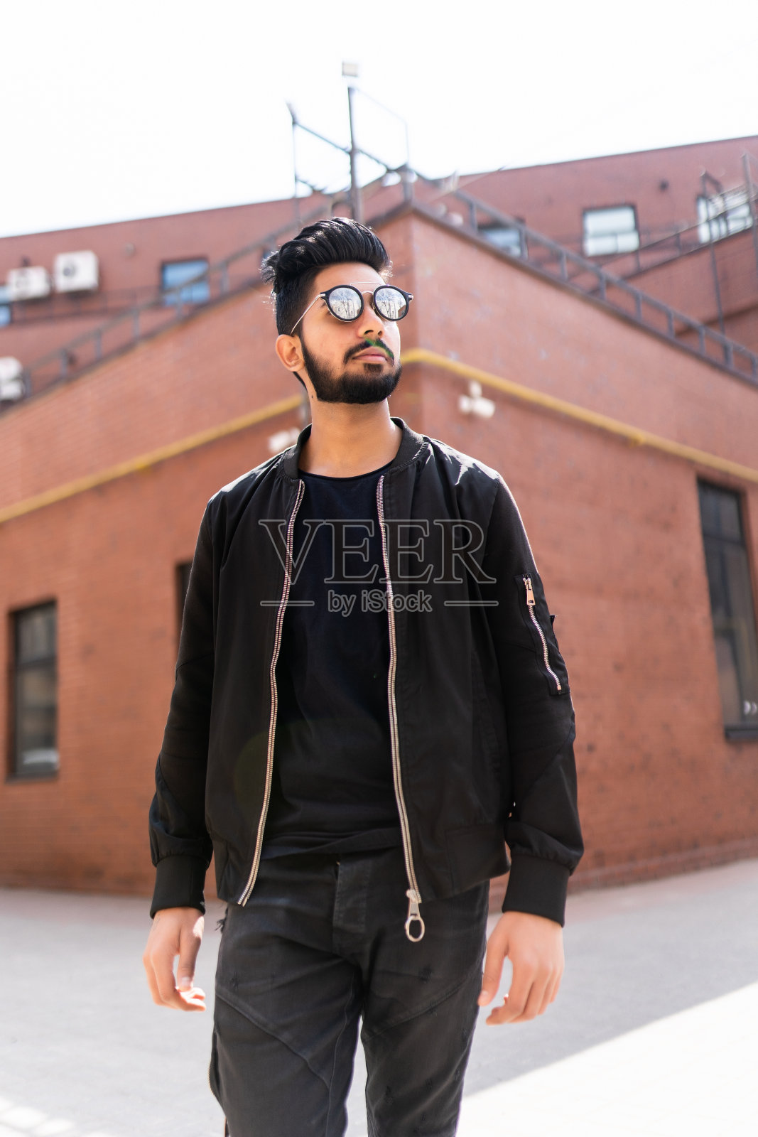 戴太阳镜站在街上的年轻印度男子照片摄影图片