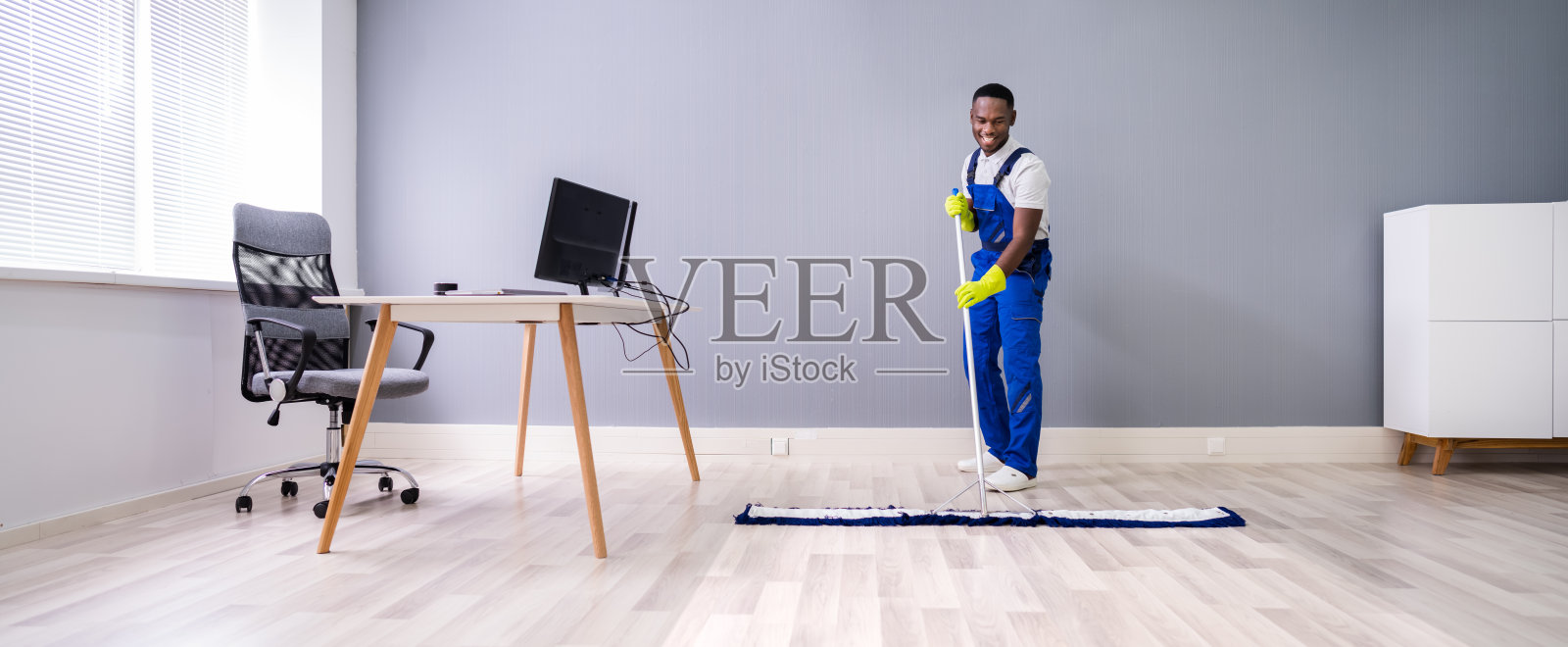 在办公室清洁地板的男清洁工照片摄影图片