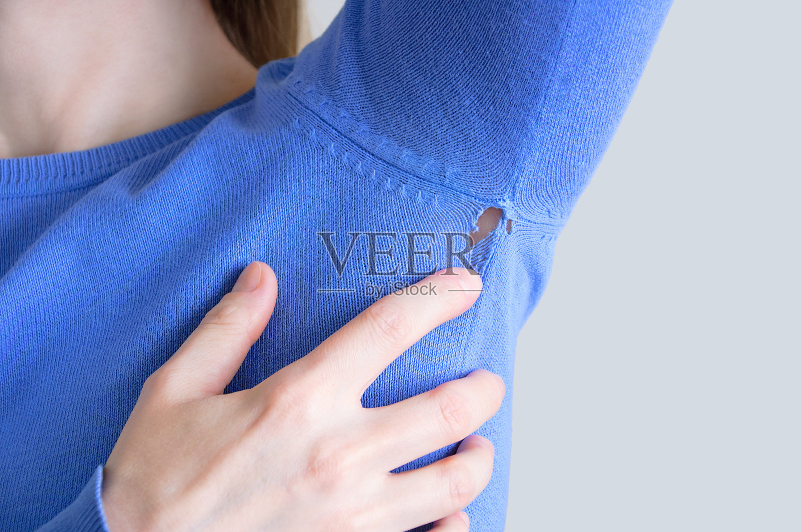 蓝色衣服上的洞。穿着运动衫的白人女人。照片摄影图片