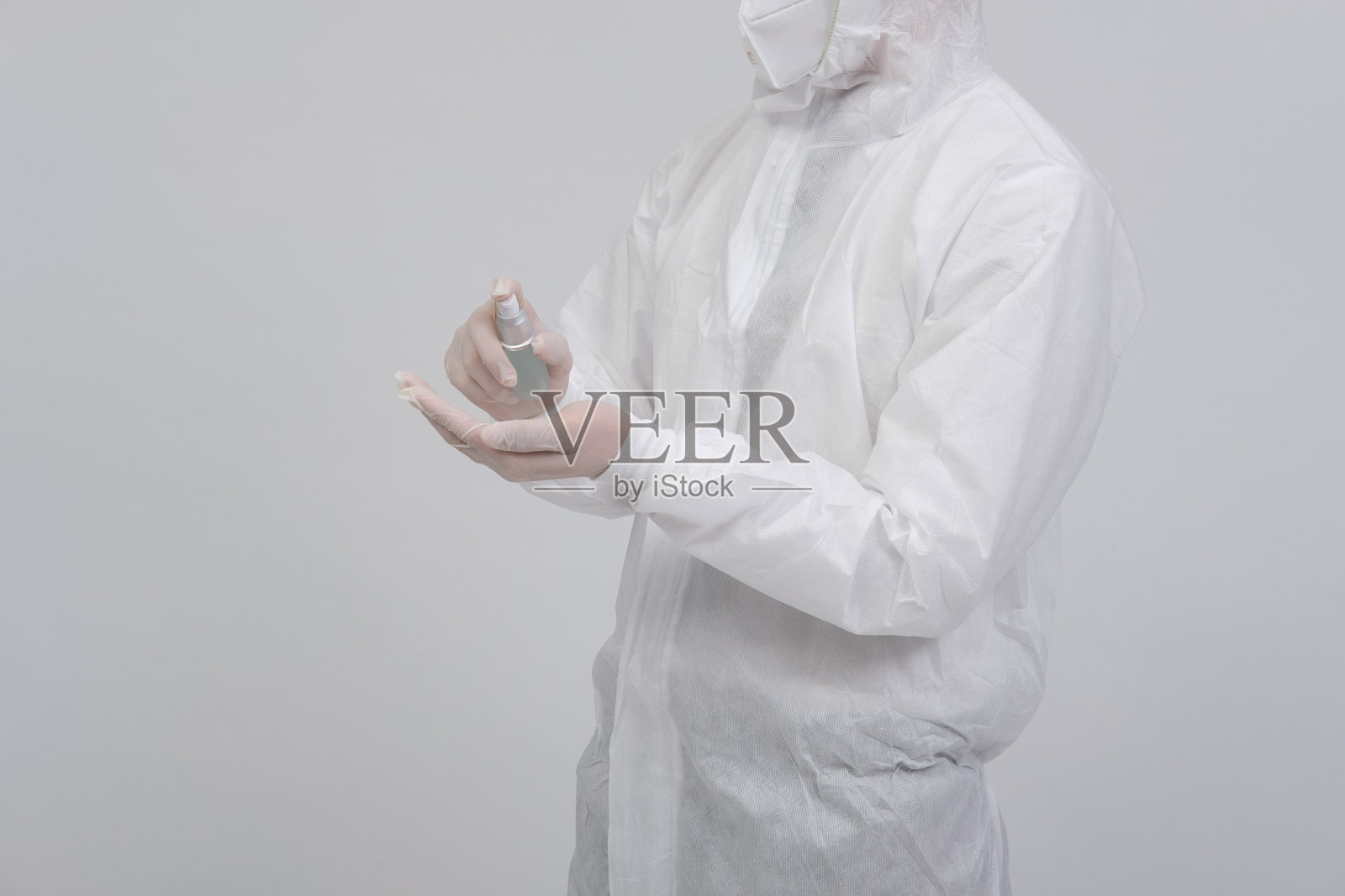 男科学家穿着生物防护制服套装,面罩,手套,带有洗手液的分发器为病毒和细菌消毒照片摄影图片