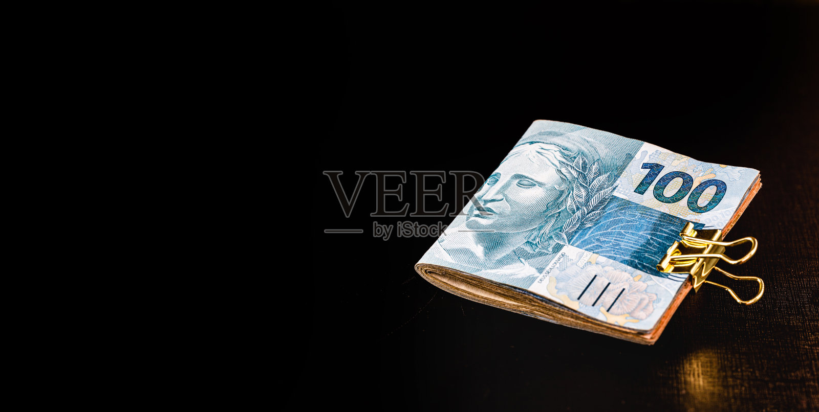 一百雷亚尔和五十雷亚尔的钞票,还有一个真正的硬币,来自巴西的货币。孤立在黑色背景上。金融危机和股市崩盘的概念。照片摄影图片