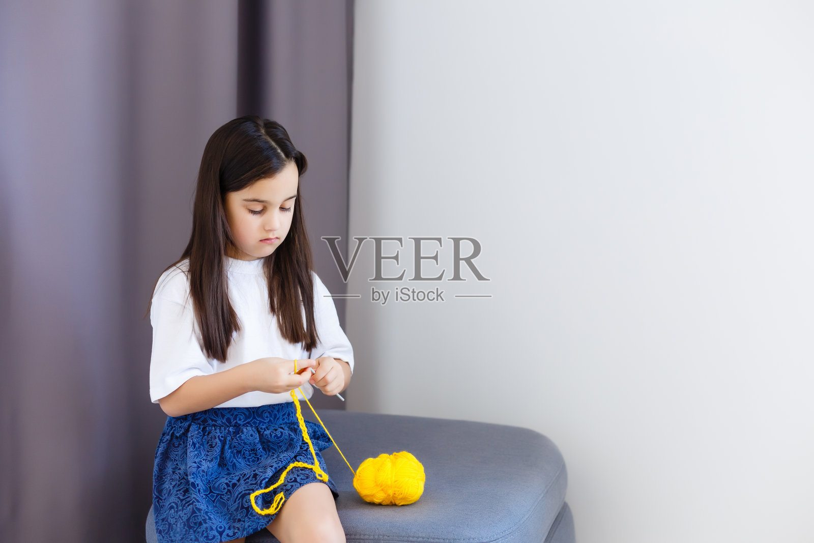 小女孩用黄色线钩织照片摄影图片