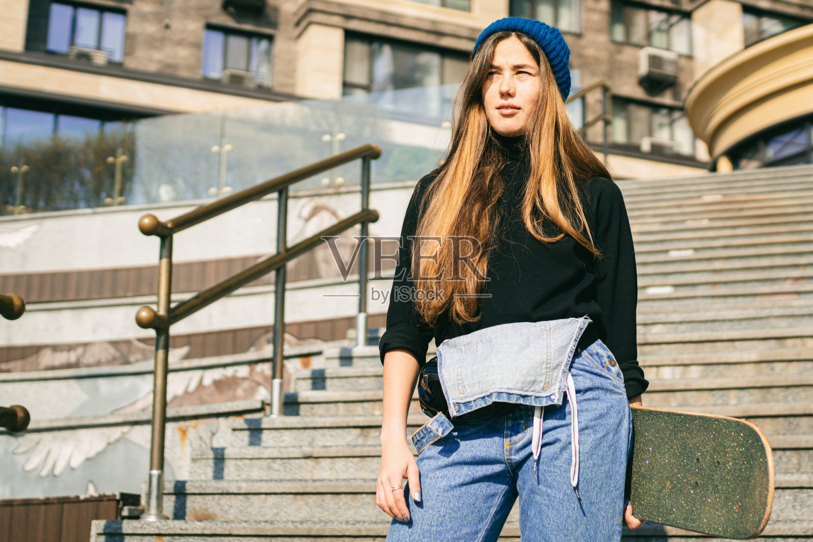 年轻白人女子手持滑板在街头摆姿势,城市环境中的青少年极限运动照片摄影图片