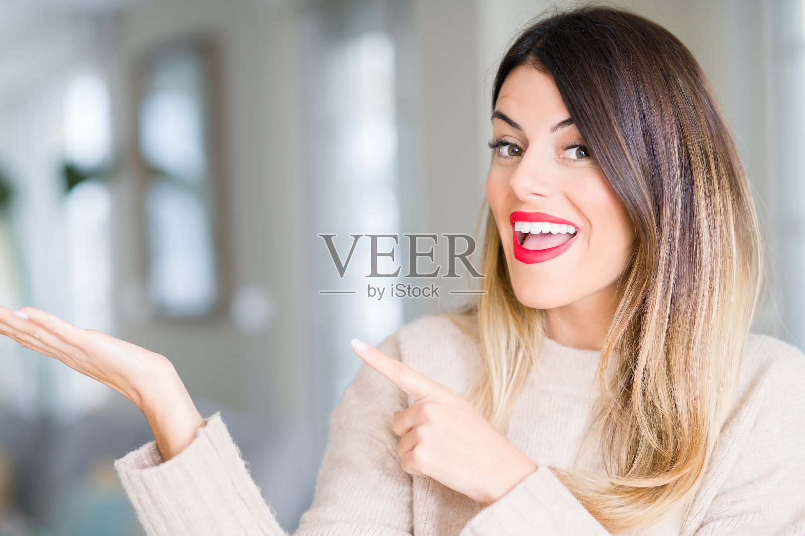 年轻美丽的女子穿着冬季毛衣在家惊奇和微笑的相机,同时提出与手指。照片摄影图片