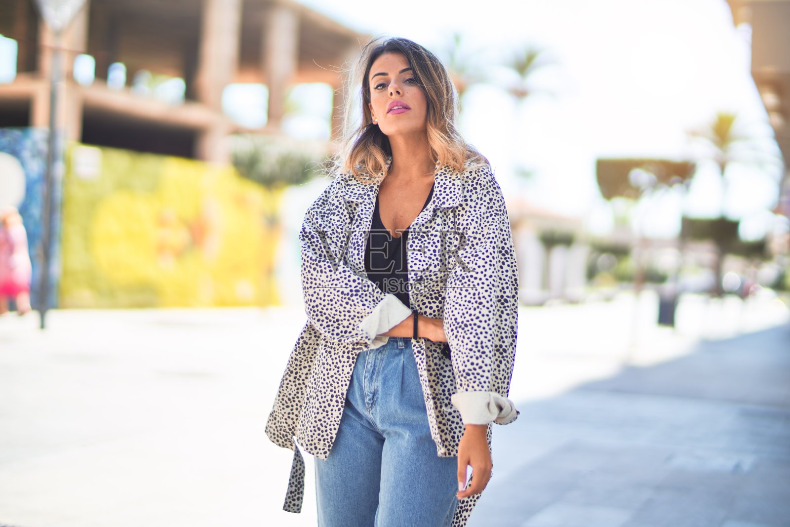 年轻漂亮的女人微笑着,快乐而自信。在镇上的街道上站立和行走照片摄影图片