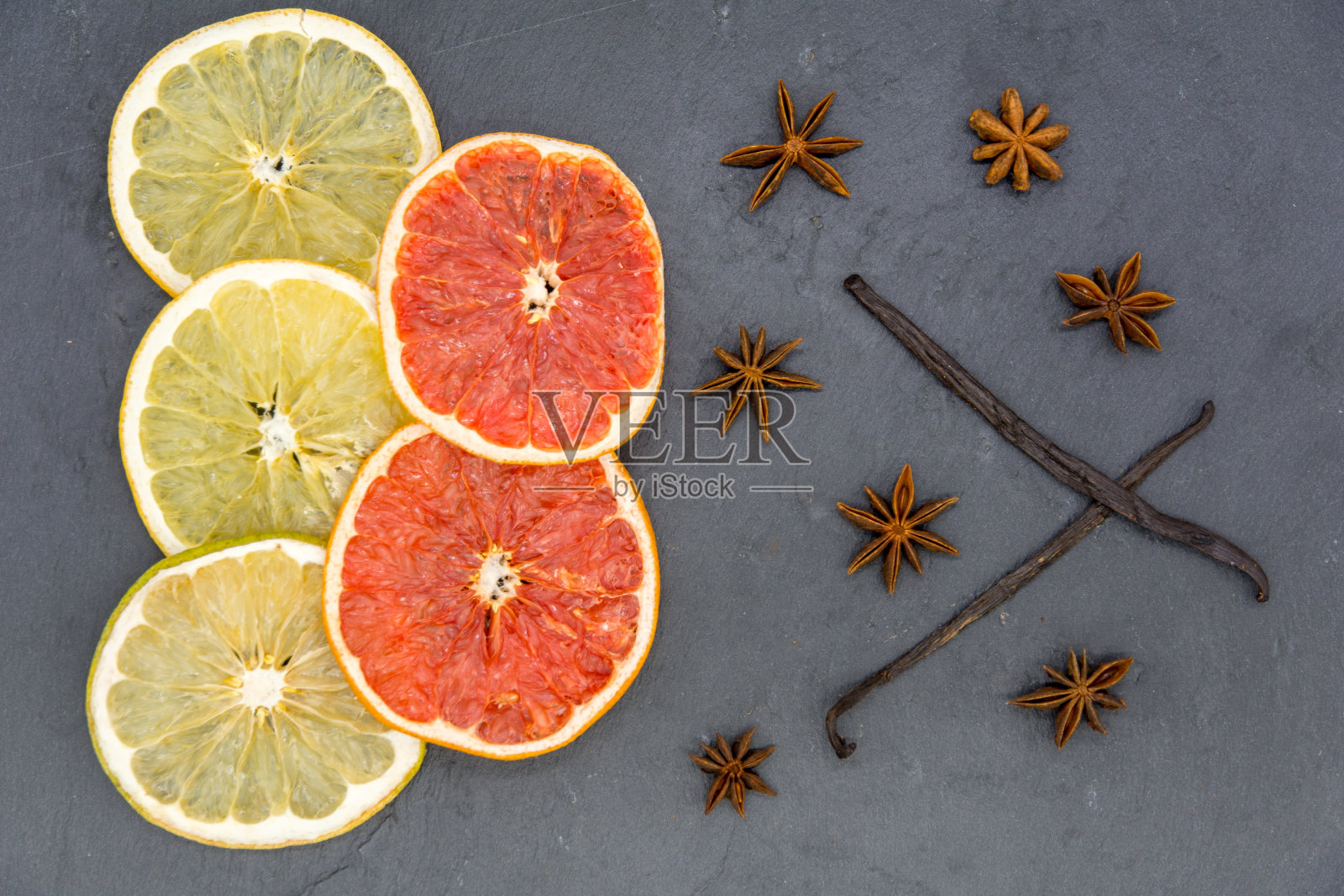 干柑橘片和各种香料在黑色石板照片摄影图片
