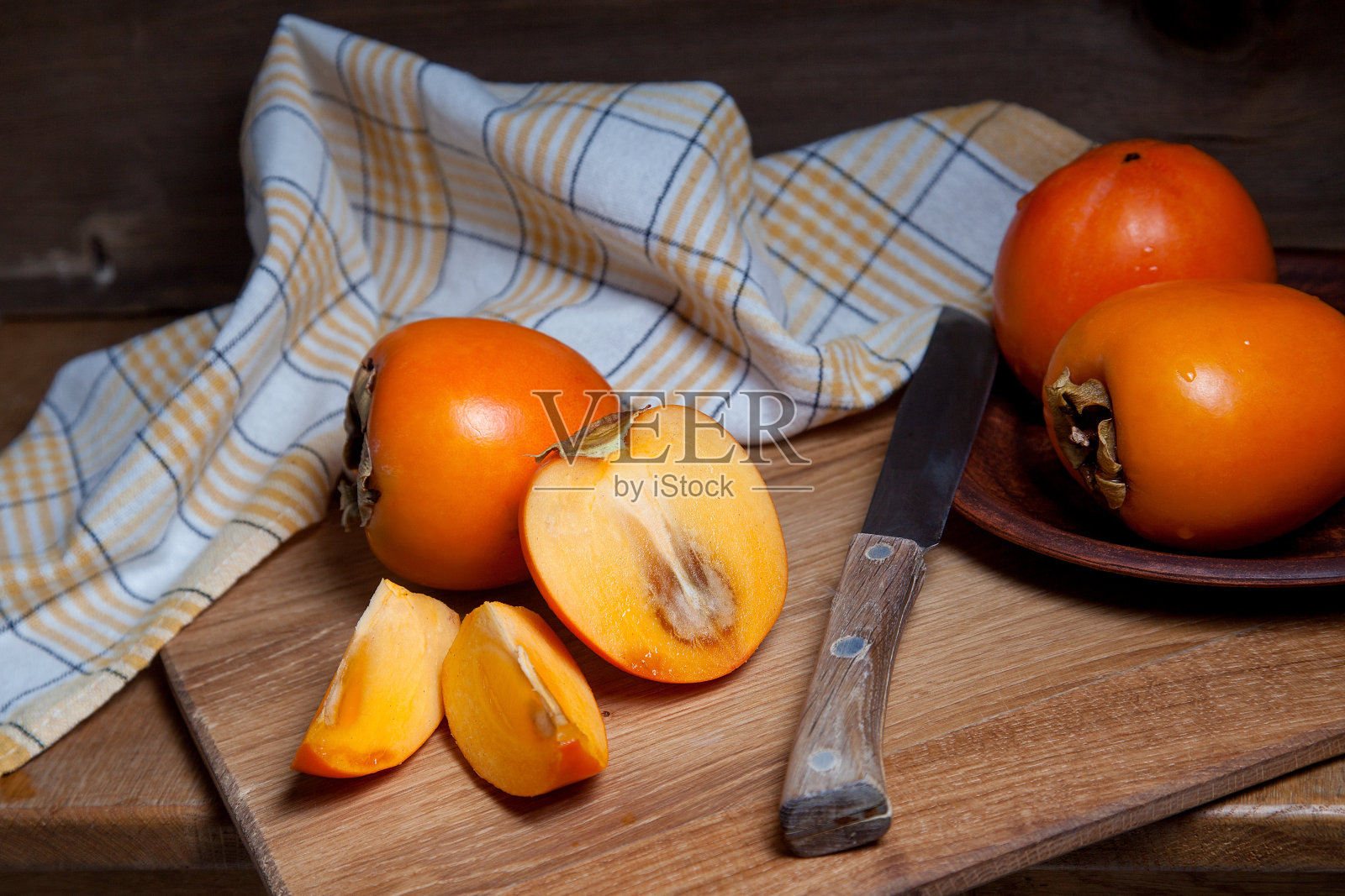整个成熟的柿子和切片的水果放在木质背景上。照片摄影图片