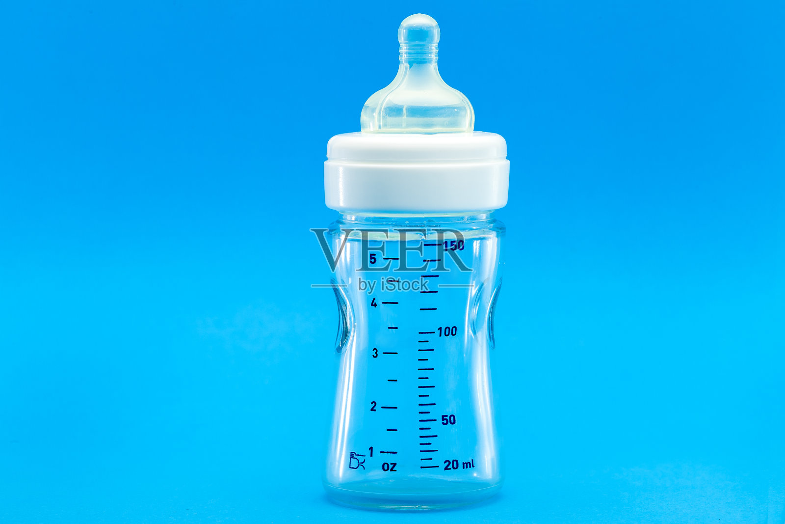 一个带磅秤的玻璃瓶和一个硅胶奶嘴,用于喂养婴儿,一个透明的隔离在蓝色背景与复制空间。照片摄影图片