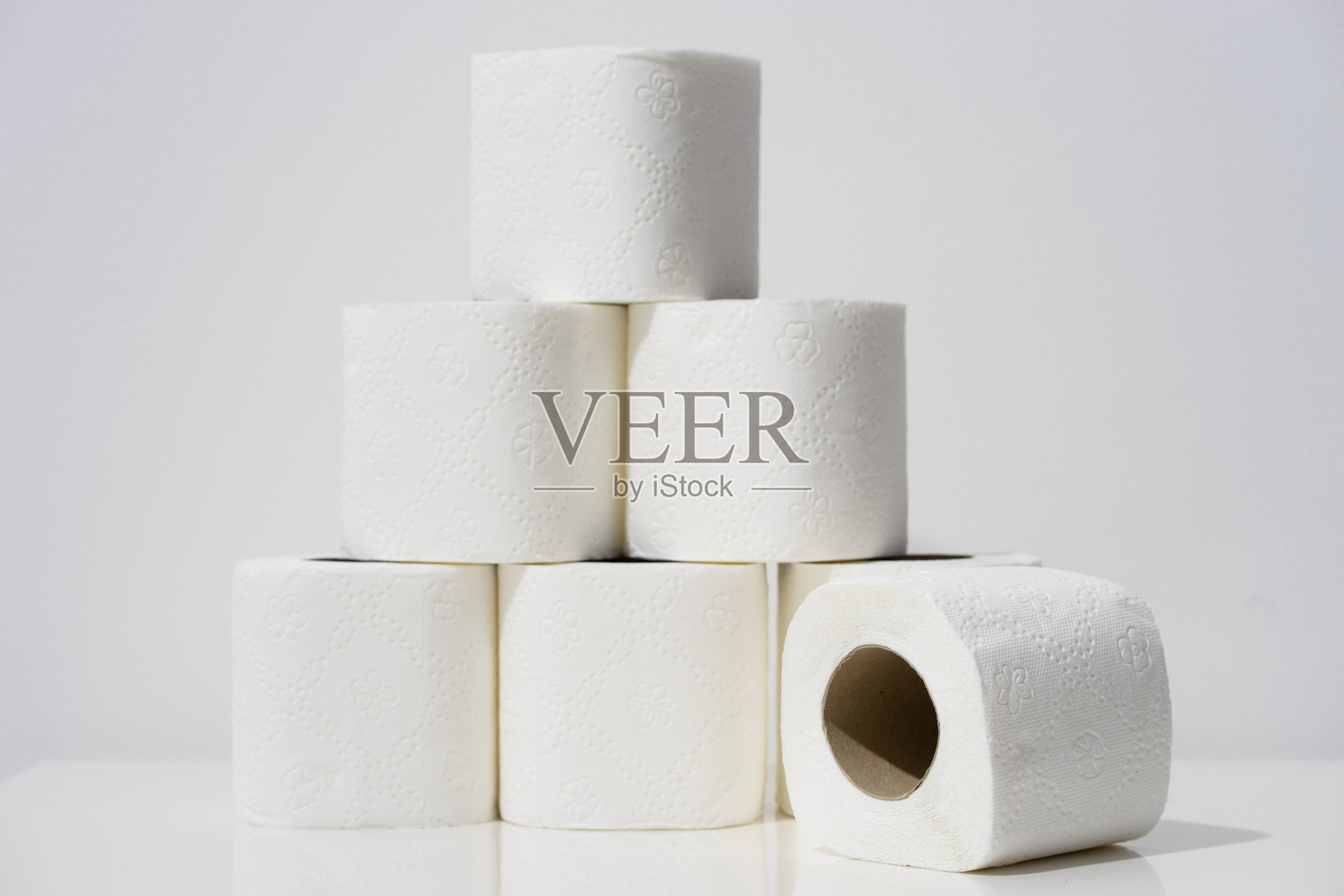 前视图上的白色卫生纸卷堆放在桌子前的墙壁背景照片摄影图片