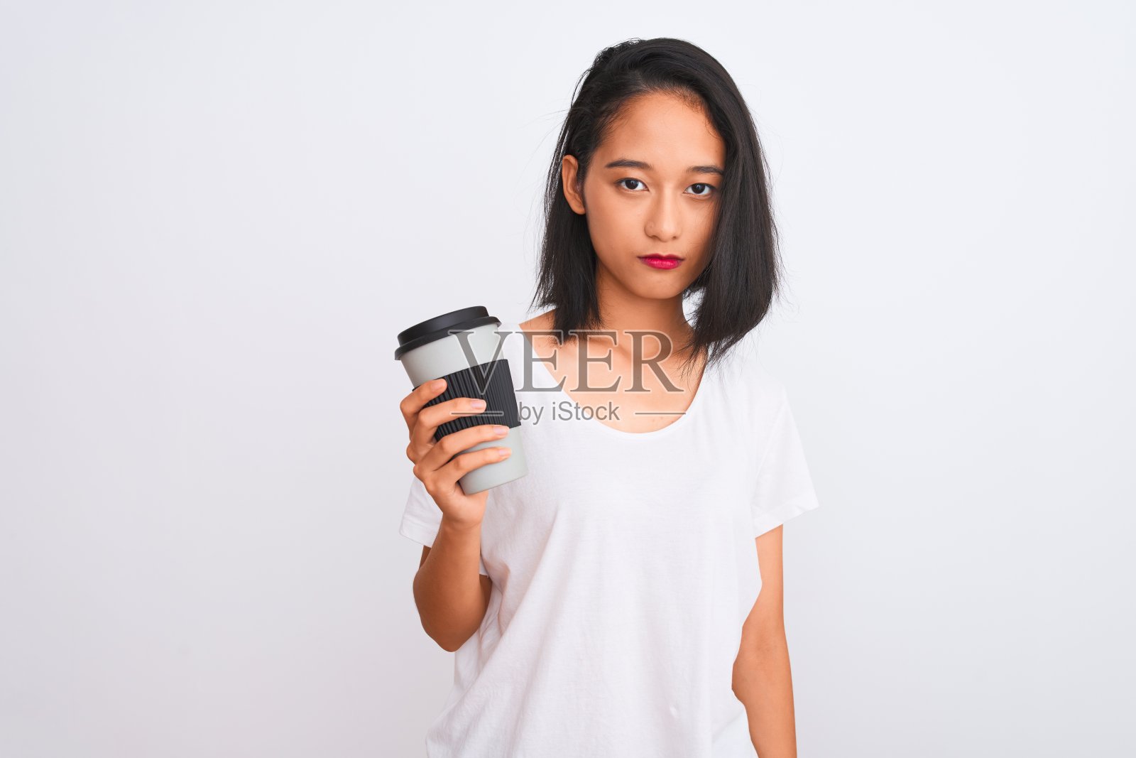 年轻的中国女人喝酒带走了一杯咖啡在孤立的白色背景与自信的表情在聪明的脸上思考严肃照片摄影图片