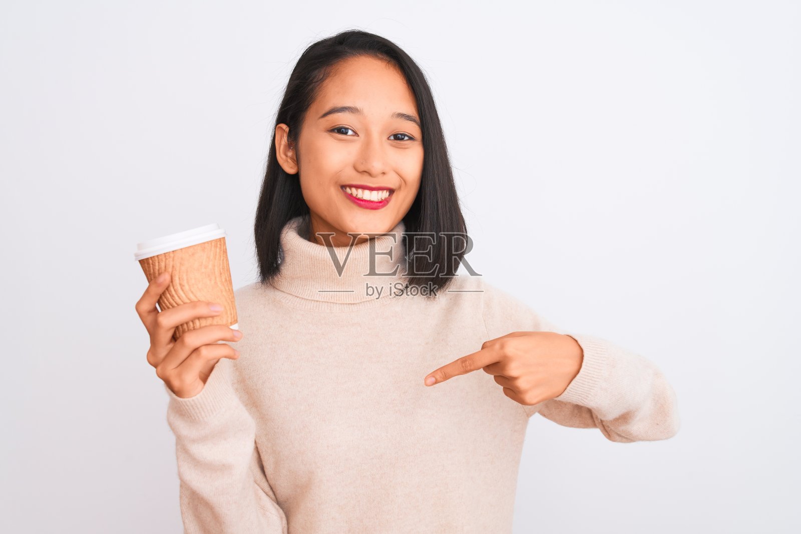 年轻美丽的中国女人喝纸杯咖啡在孤立的白色背景与惊讶的脸指向自己照片摄影图片