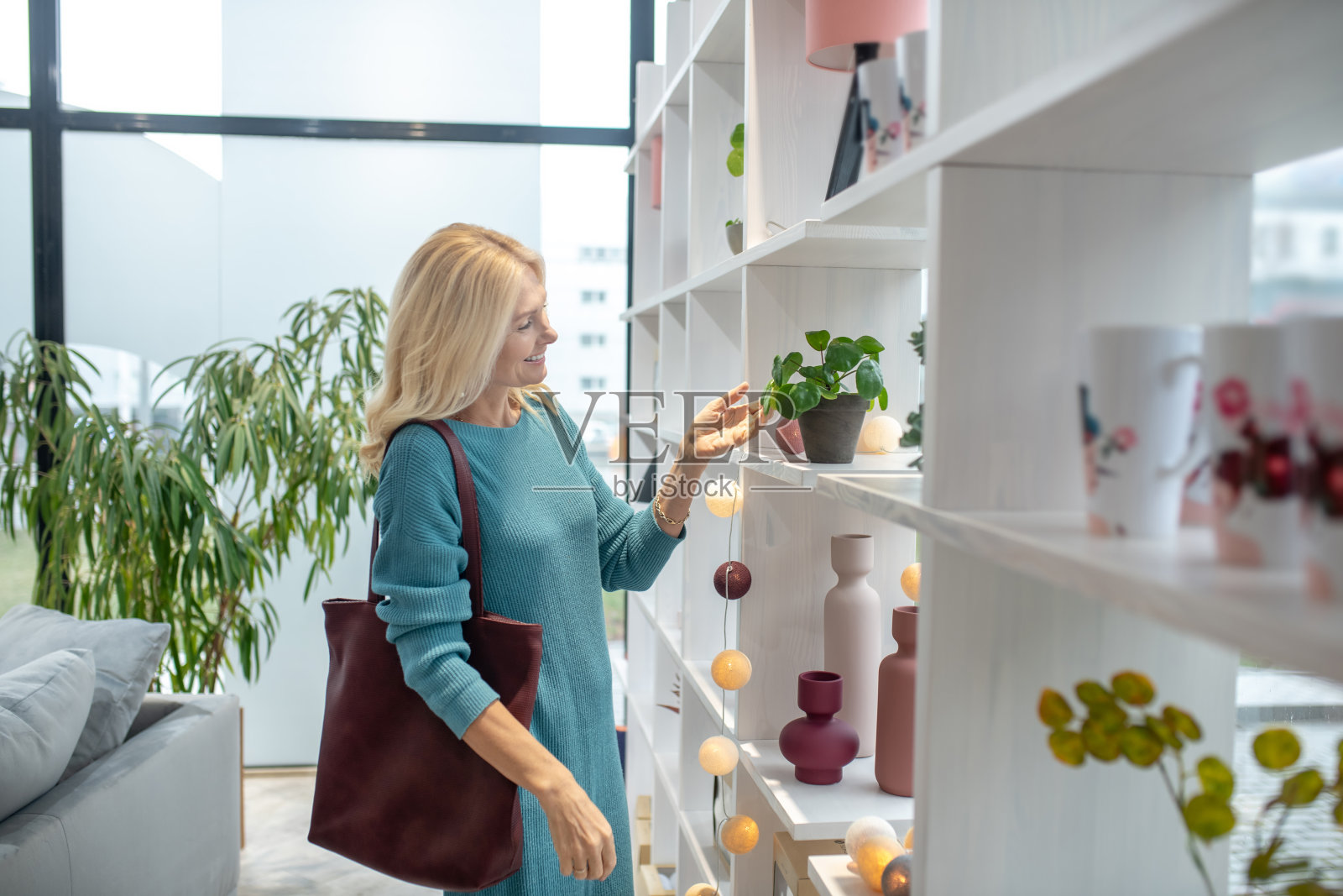 一个穿着蓝色裙子的女人站在一个高高的衣架旁。照片摄影图片