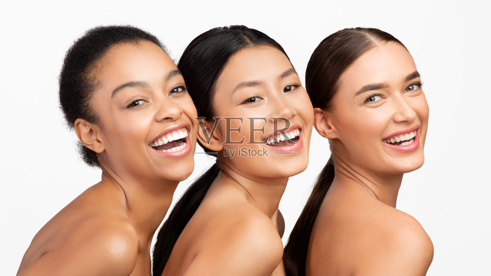 三个多民族女性摆出微笑的姿势对着相机,工作室拍摄,全景照片摄影图片